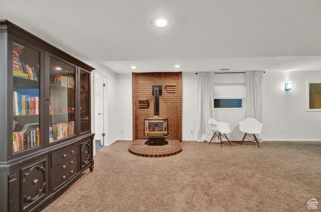 Living area with brick wall, a wood stove, and light carpet