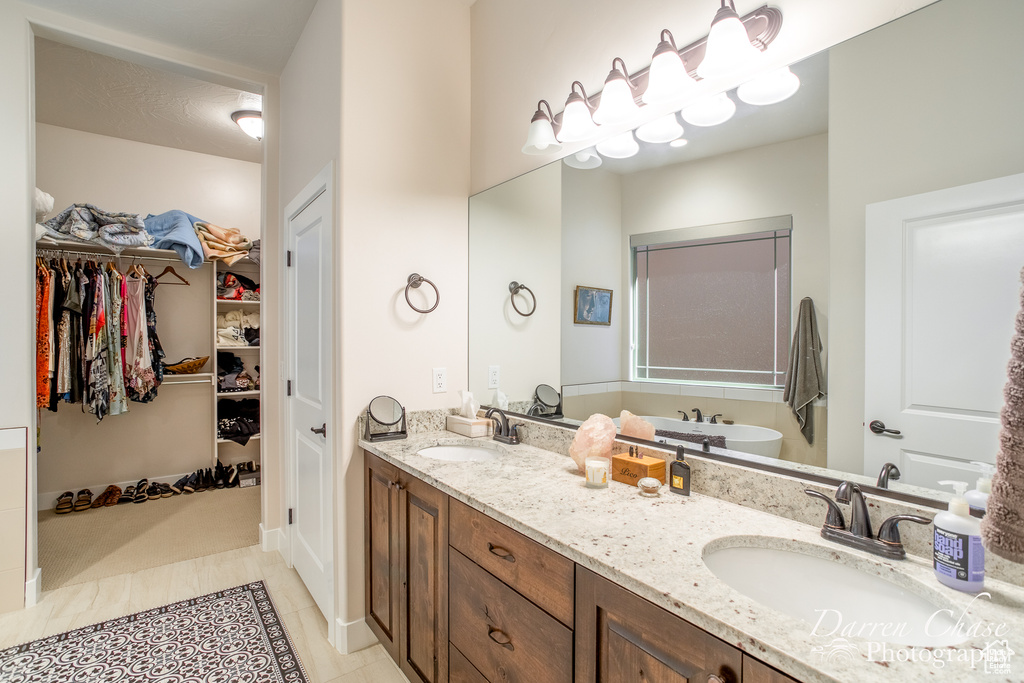 Bathroom with double sink, vanity with extensive cabinet space, and tile flooring