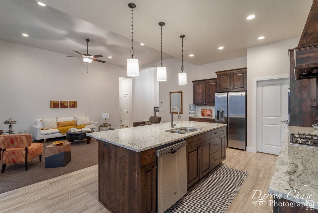 Kitchen featuring a center island with sink, ceiling fan, light colored carpet, sink, and appliances with stainless steel finishes