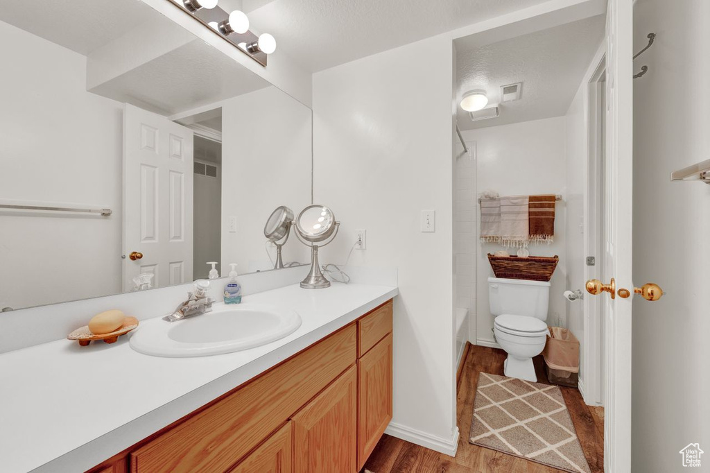 Full bathroom featuring oversized vanity, toilet, shower / bath combination, and hardwood / wood-style floors