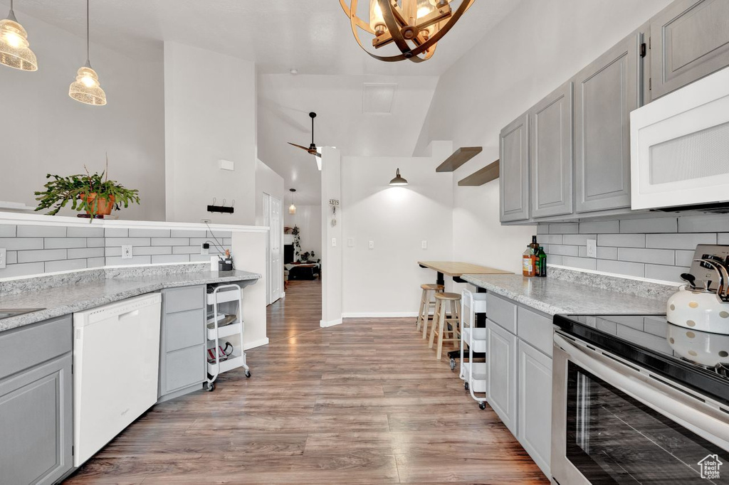 Kitchen featuring light hardwood / wood-style floors, white appliances, tasteful backsplash, and light stone counters