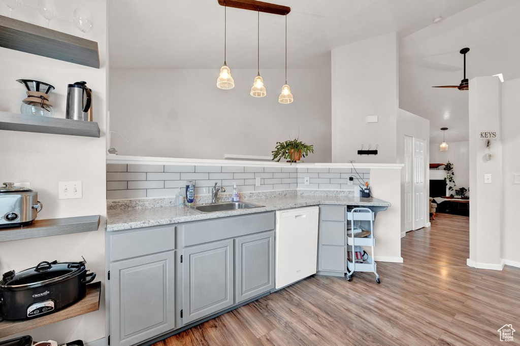 Kitchen featuring pendant lighting, sink, dishwasher, light hardwood / wood-style flooring, and tasteful backsplash