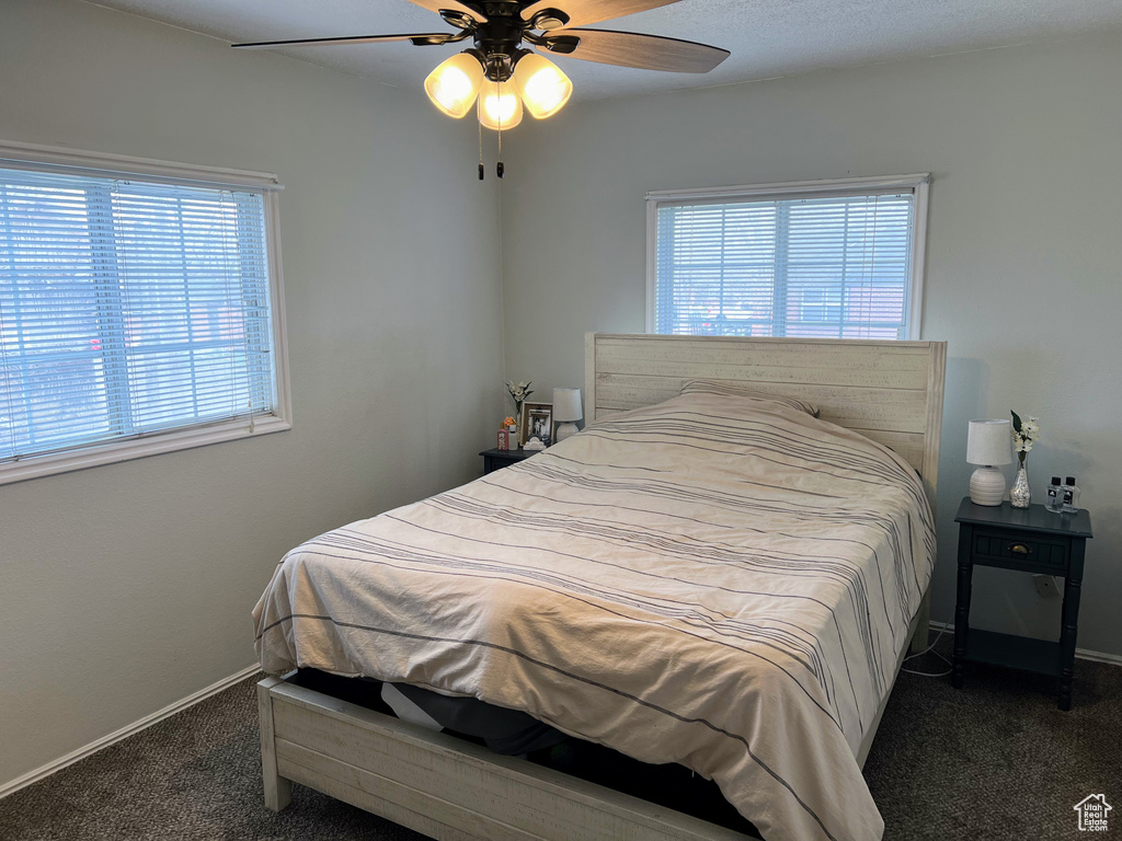 Bedroom featuring dark carpet, multiple windows, and ceiling fan