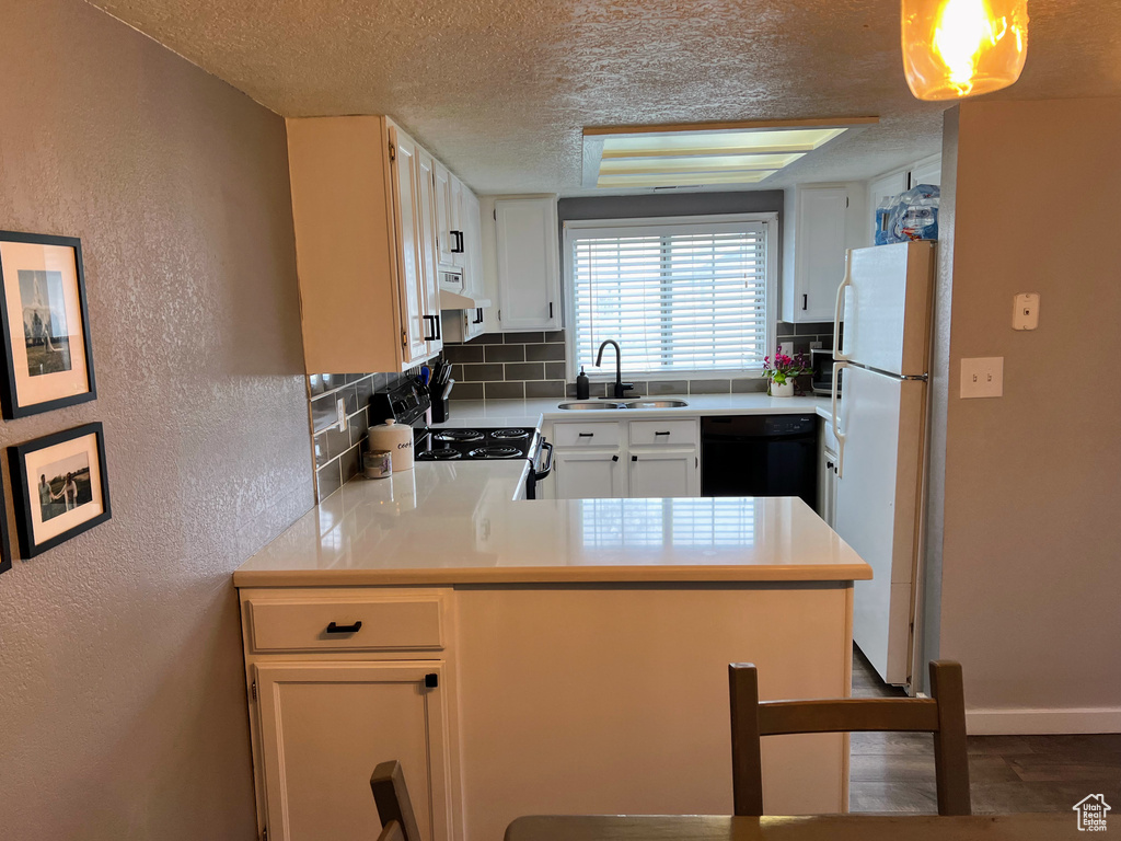 Kitchen with kitchen peninsula, backsplash, sink, dishwasher, and white refrigerator
