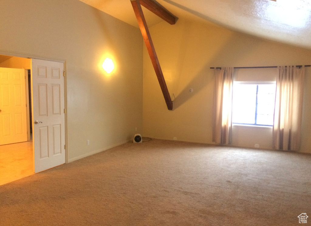 Additional living space featuring lofted ceiling with beams and light colored carpet