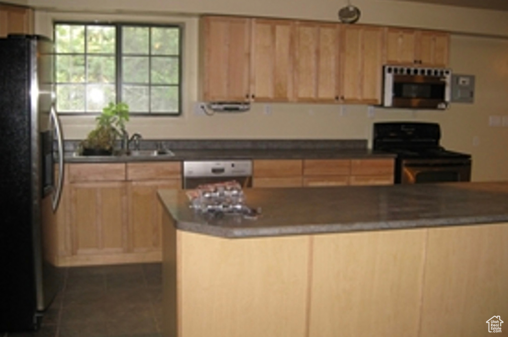 Kitchen with light brown cabinetry, white dishwasher, stainless steel fridge, and stove
