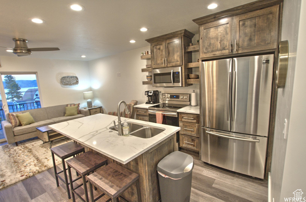Kitchen featuring stainless steel appliances, ceiling fan, sink, and dark wood-type flooring