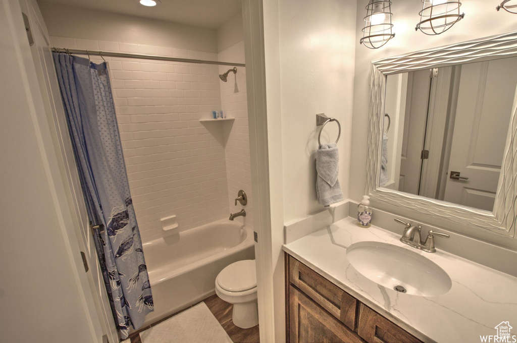 Full bathroom featuring shower / tub combo, vanity, wood-type flooring, and toilet
