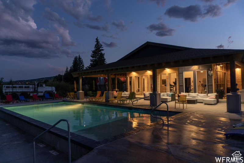 Pool at dusk featuring an outdoor hangout area and a patio area