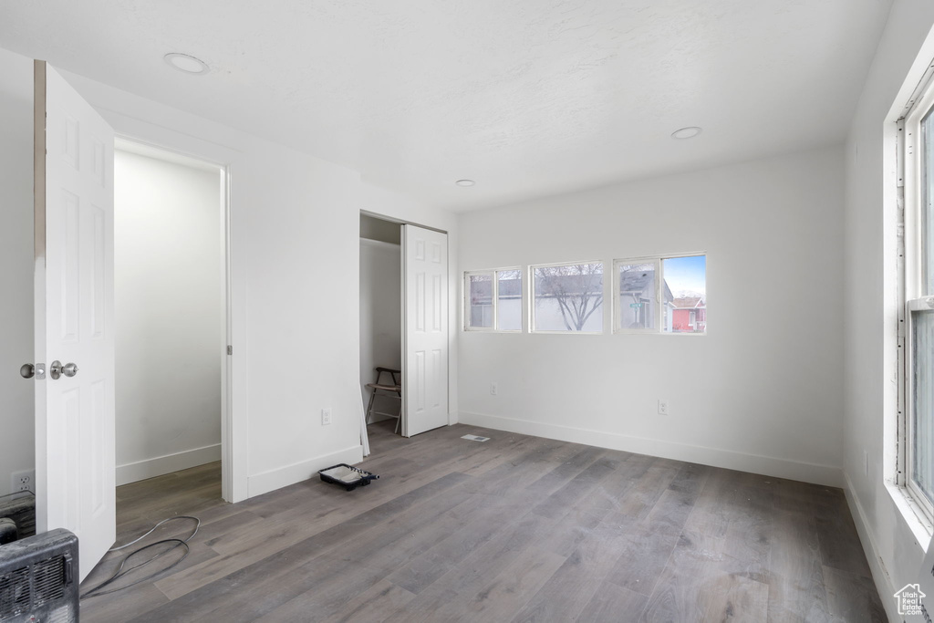 Unfurnished bedroom with a closet, hardwood / wood-style floors, and multiple windows