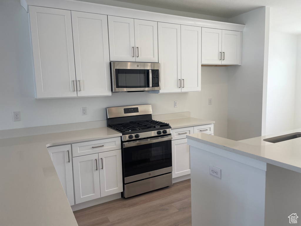 Kitchen featuring white cabinetry, light hardwood / wood-style floors, and appliances with stainless steel finishes
