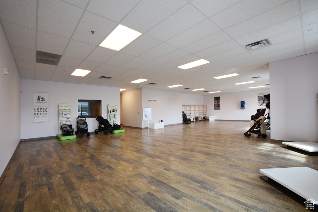 Workout area featuring a paneled ceiling and dark wood-type flooring