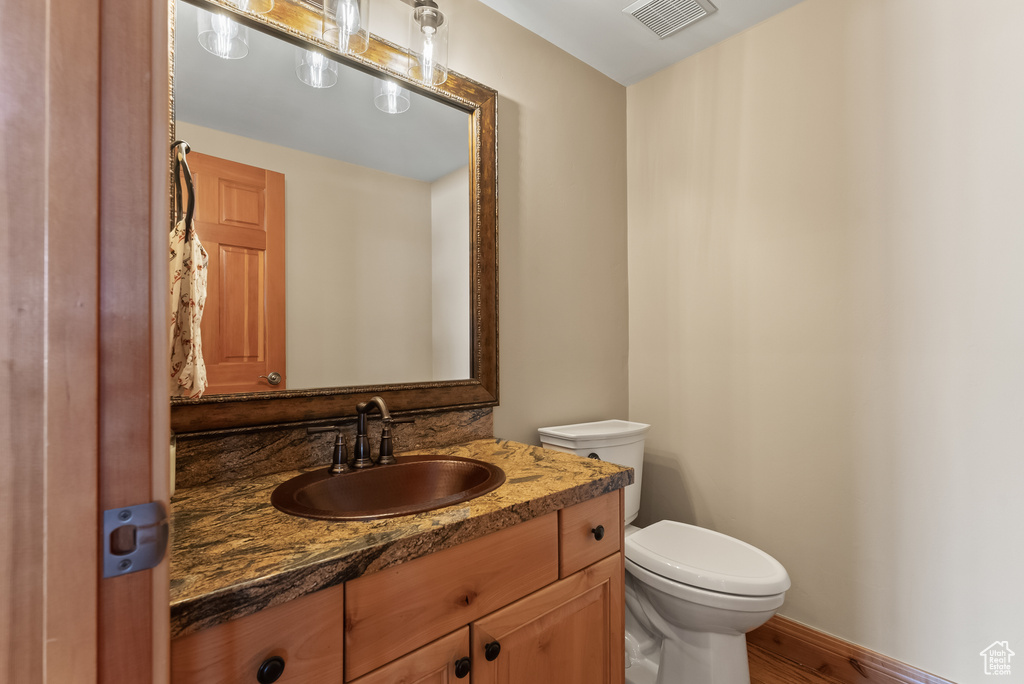 Bathroom with hardwood / wood-style flooring, oversized vanity, and toilet