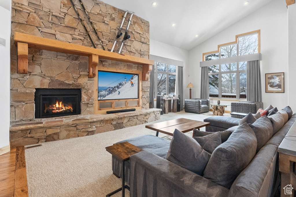 Living room featuring high vaulted ceiling, wood-type flooring, and a stone fireplace