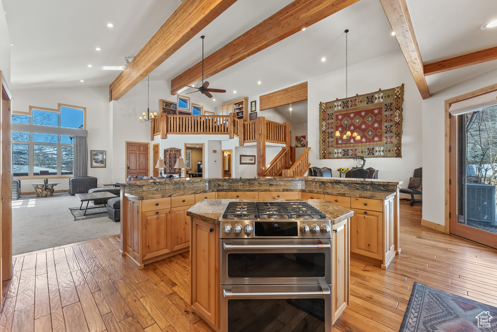 Kitchen featuring range with two ovens, a kitchen island, dark stone countertops, and ceiling fan with notable chandelier