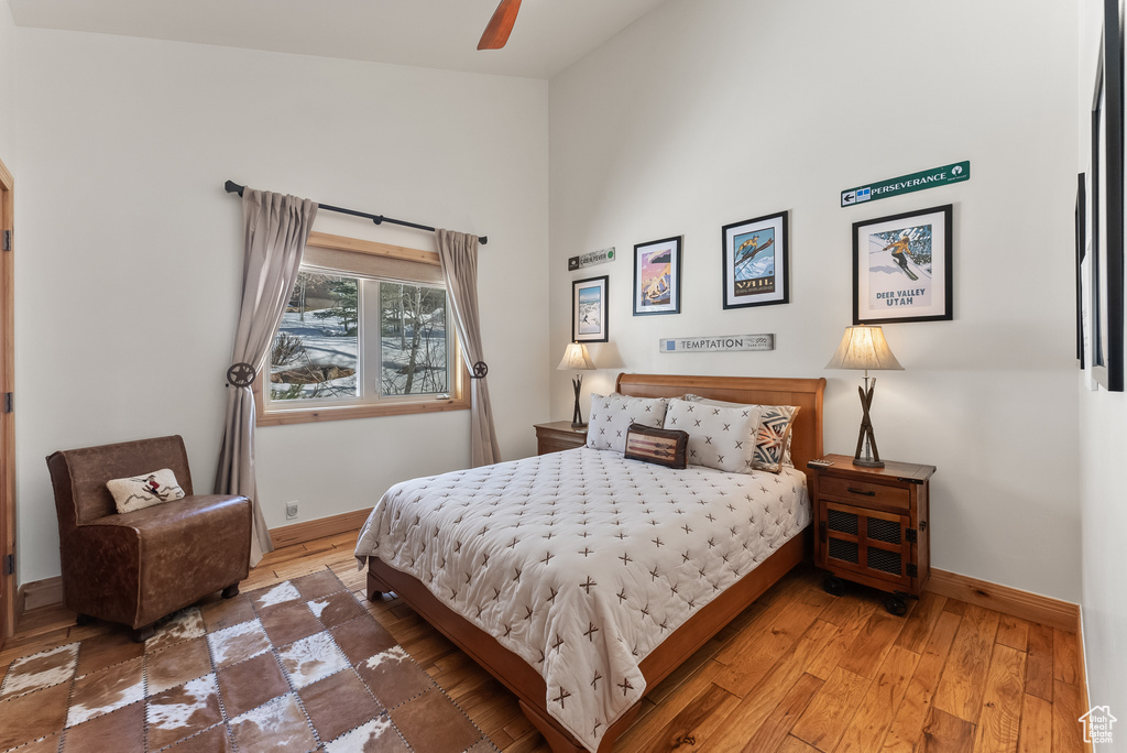 Bedroom with hardwood / wood-style floors, high vaulted ceiling, and ceiling fan