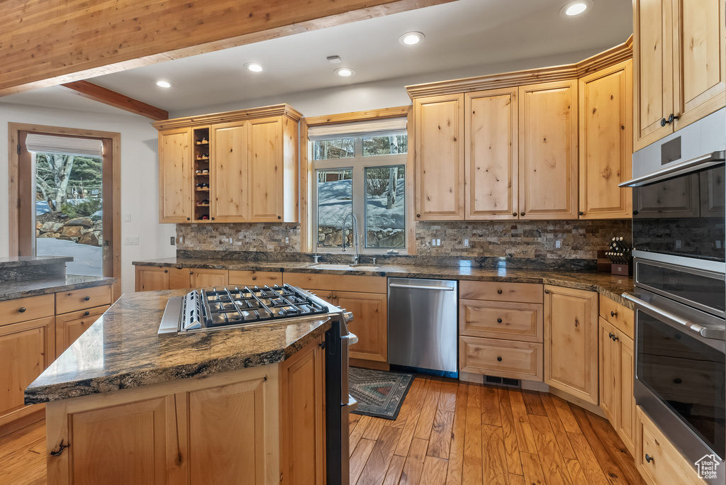 Kitchen featuring light brown cabinets, stainless steel appliances, backsplash, light wood-type flooring, and sink