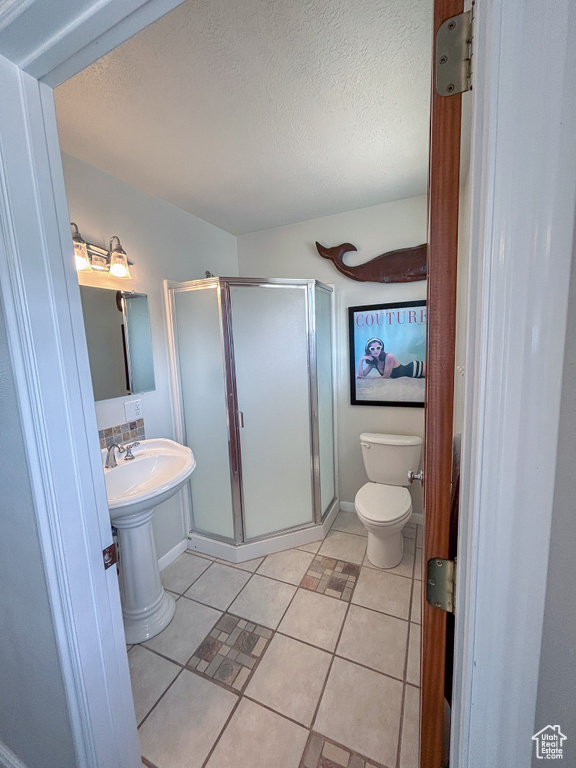 Bathroom featuring walk in shower, toilet, a textured ceiling, and tile flooring