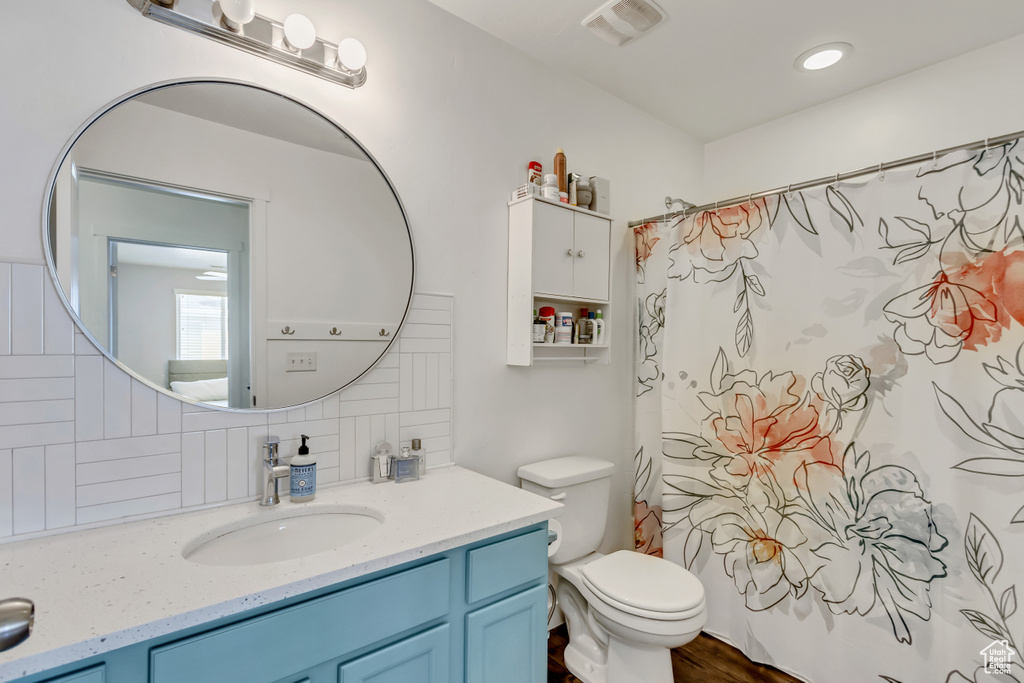 Bathroom featuring vanity, backsplash, toilet, and wood-type flooring