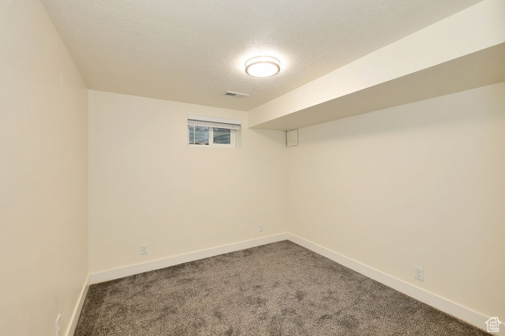 Spare room with a textured ceiling and dark colored carpet