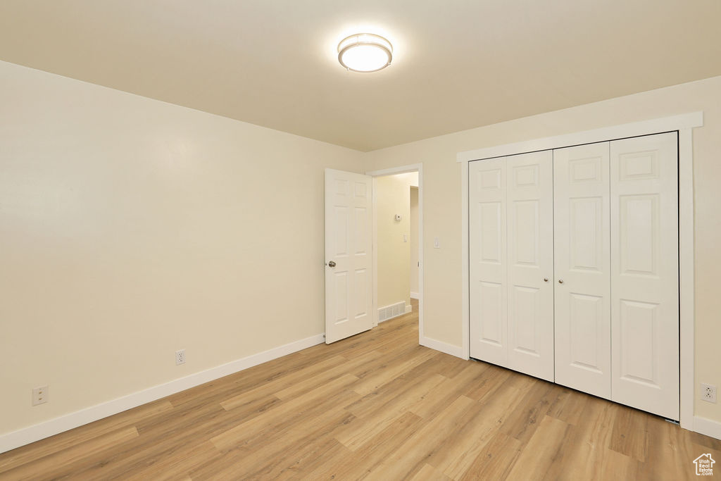 Unfurnished bedroom with a closet and light wood-type flooring