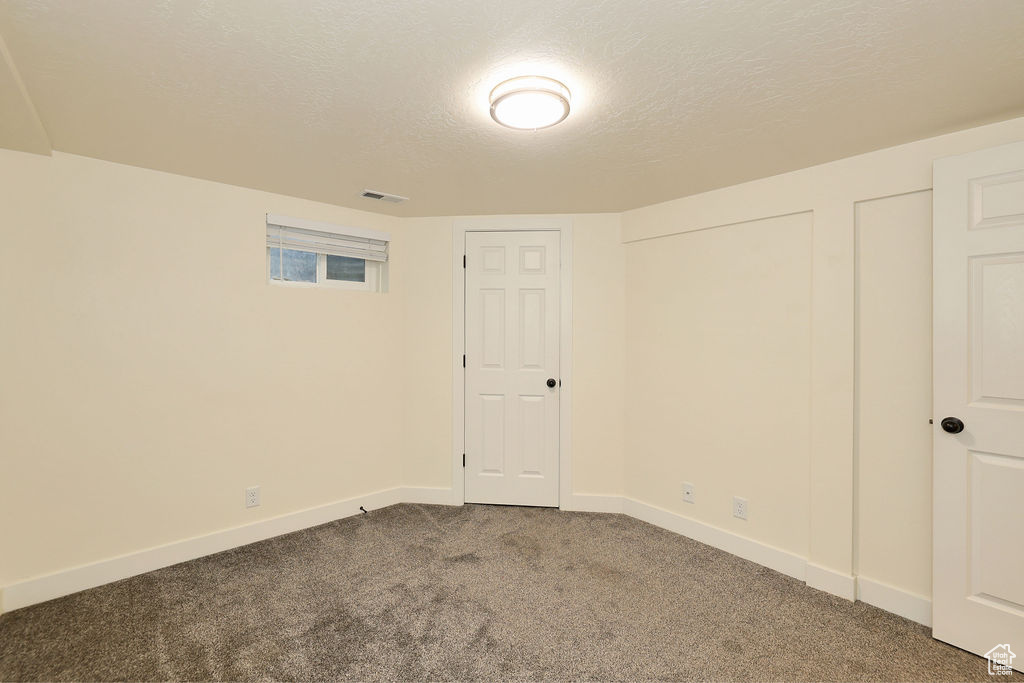 Interior space with two closets, a textured ceiling, and dark carpet