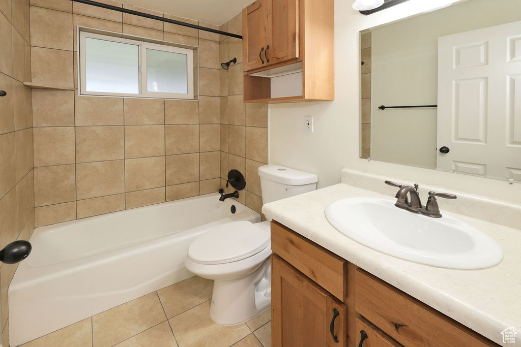 Full bathroom with tiled shower / bath combo, toilet, vanity, and tile flooring