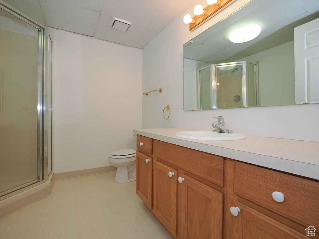 Bathroom featuring toilet, large vanity, walk in shower, and tile flooring
