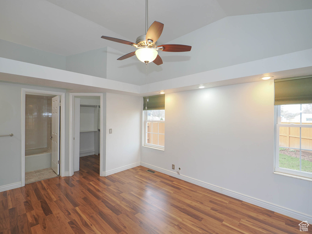 Unfurnished bedroom with ensuite bath, a walk in closet, ceiling fan, and dark hardwood / wood-style floors