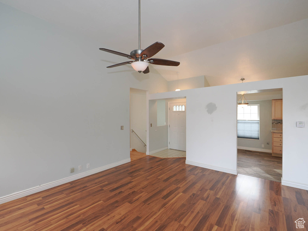 Empty room with dark tile flooring, ceiling fan, and high vaulted ceiling
