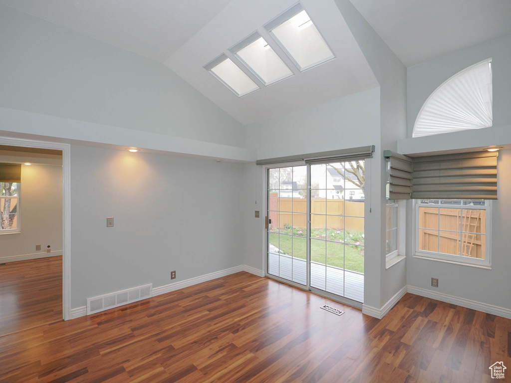 Spare room with high vaulted ceiling and dark hardwood / wood-style flooring