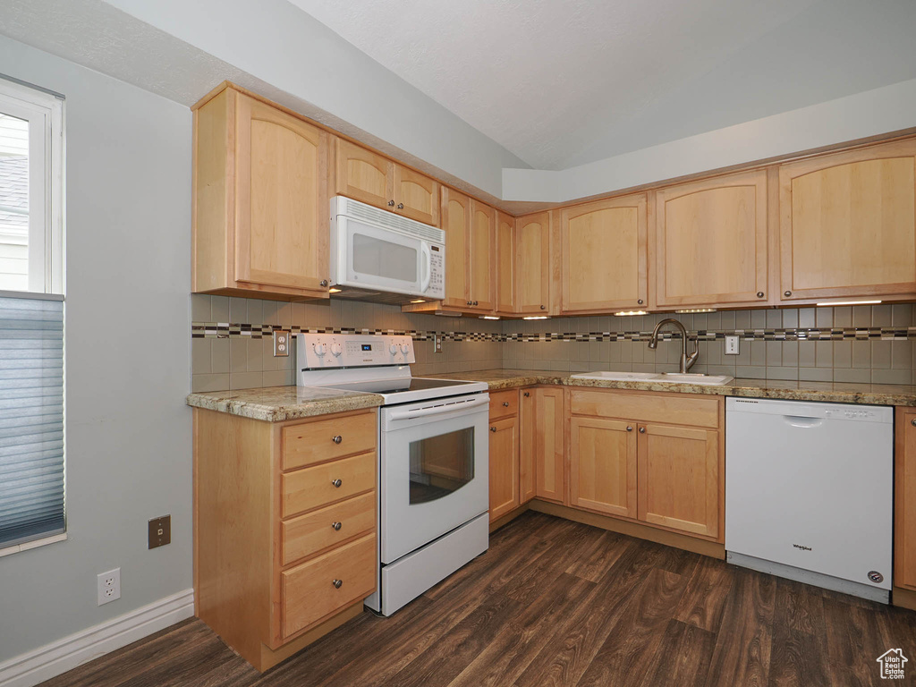 Kitchen with light brown cabinets, tasteful backsplash, dark wood-type flooring, white appliances, and sink