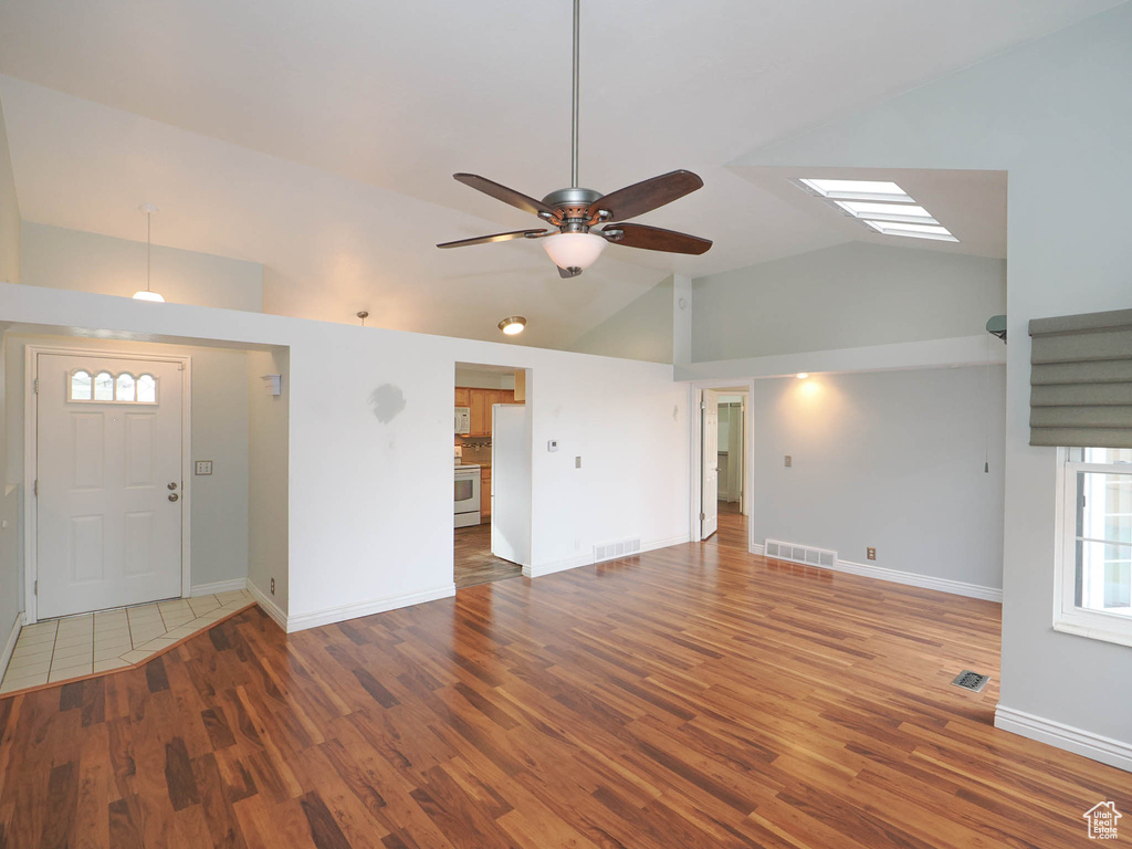Empty room featuring hardwood / wood-style floors, high vaulted ceiling, and ceiling fan