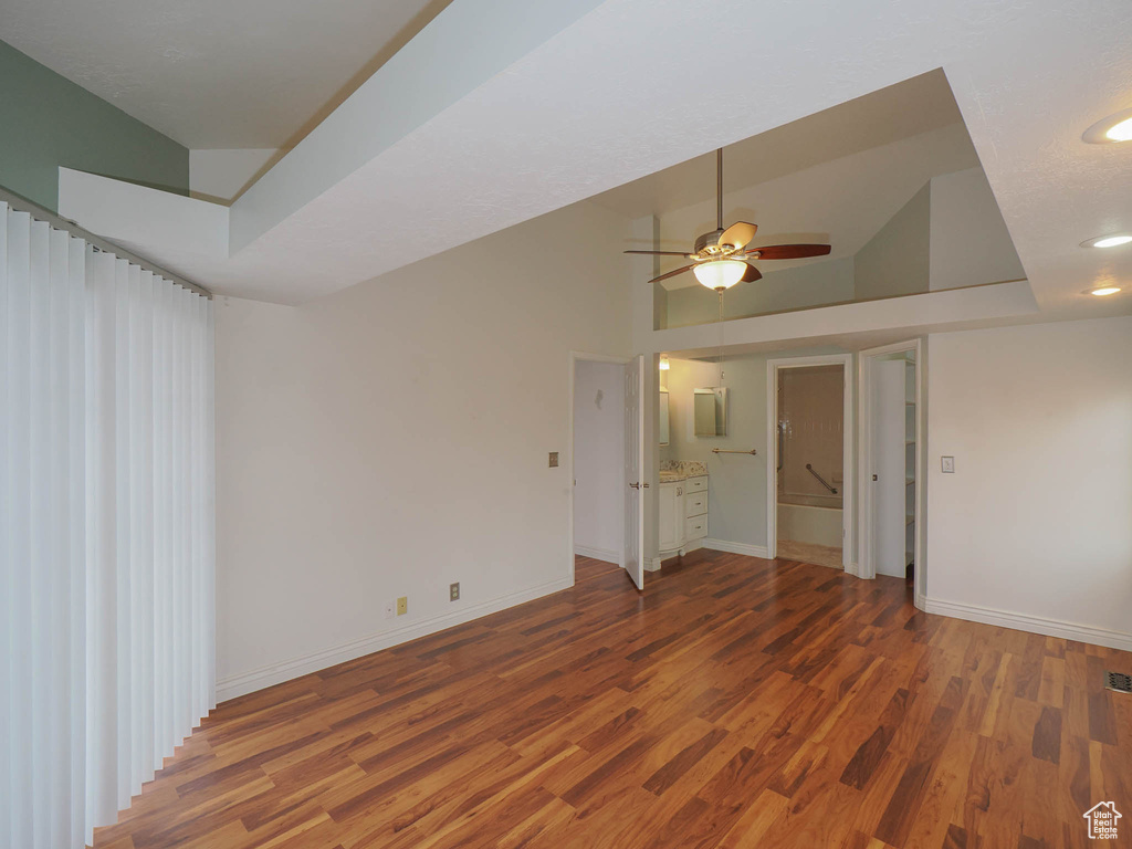 Unfurnished bedroom featuring ceiling fan, connected bathroom, hardwood / wood-style floors, and high vaulted ceiling