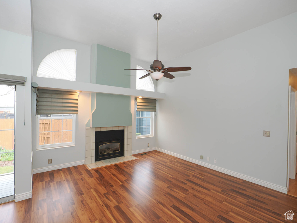 Unfurnished living room featuring dark hardwood / wood-style flooring, ceiling fan, and a wealth of natural light