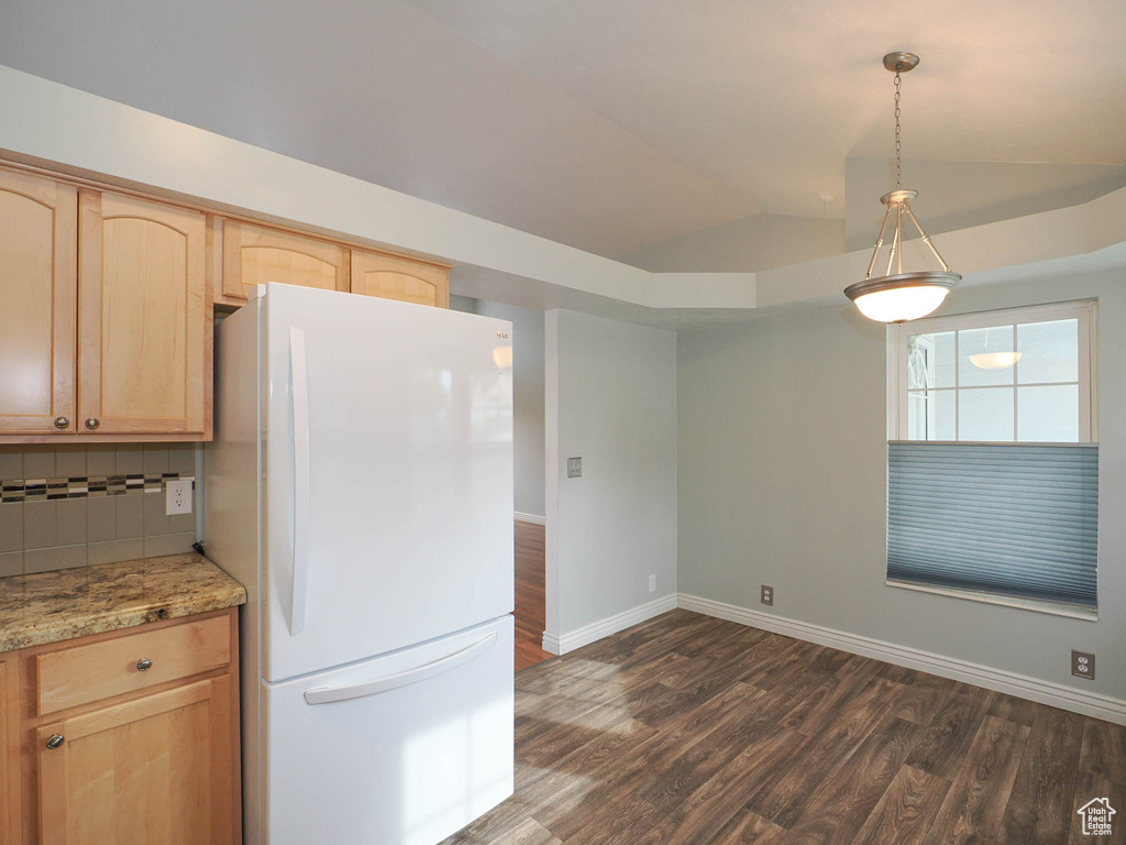 Kitchen featuring backsplash, white refrigerator, light brown cabinets, and pendant lighting