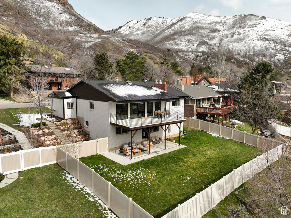Rear view of house with a balcony, a lawn, a deck with mountain view, and a patio