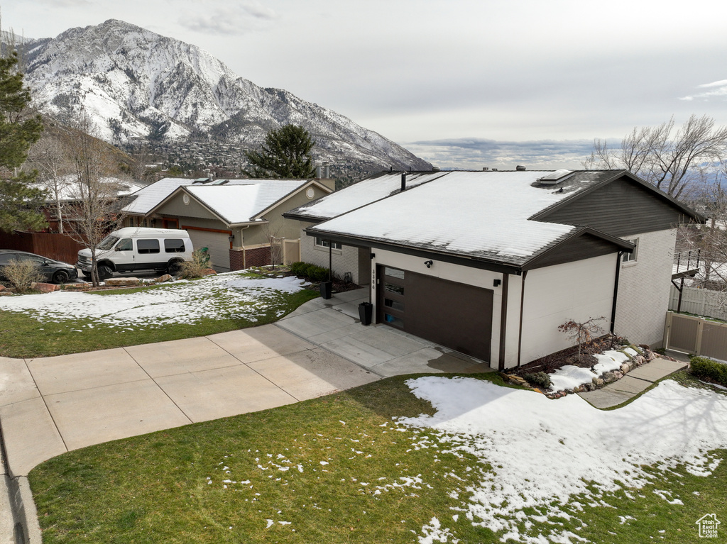 View of front of home with a mountain view, a garage, and a yard
