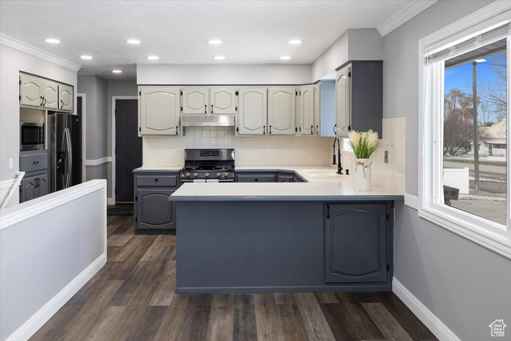 Kitchen with gray cabinetry, kitchen peninsula, dark hardwood / wood-style flooring, and appliances with stainless steel finishes