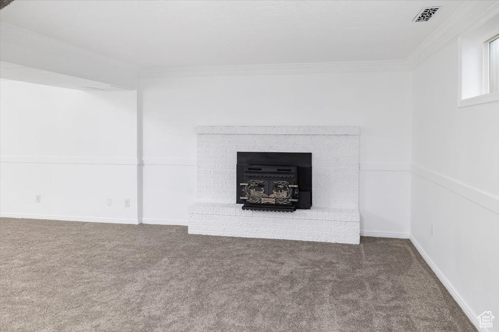 Interior space with dark carpet, a brick fireplace, and crown molding