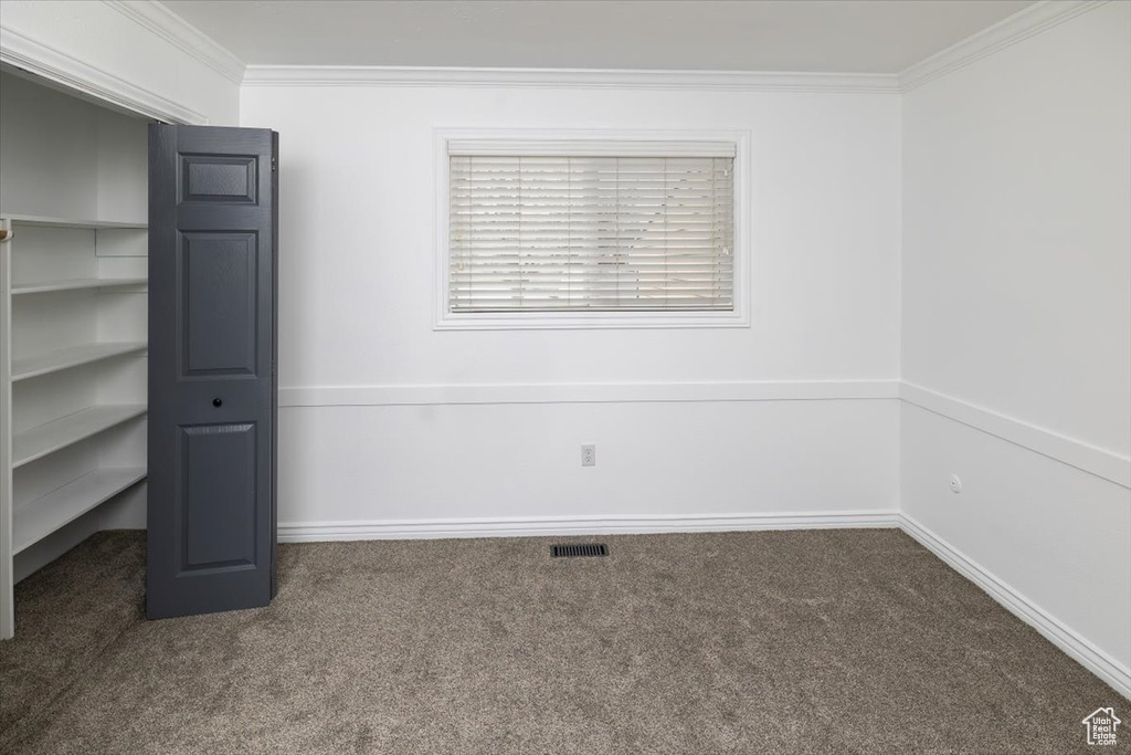 Unfurnished bedroom featuring dark colored carpet and ornamental molding
