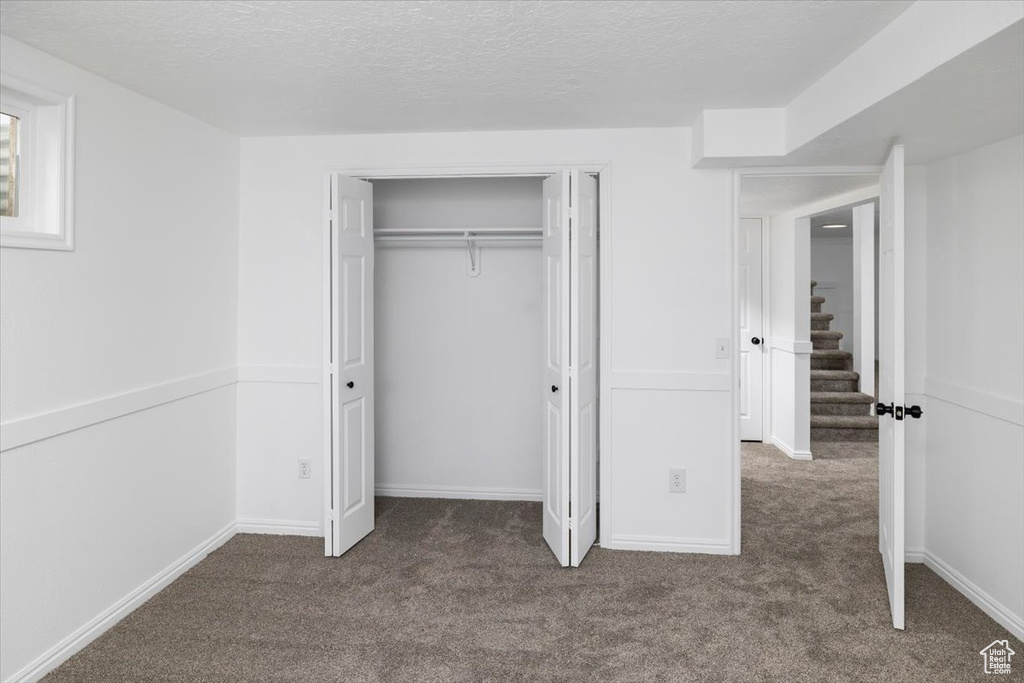 Unfurnished bedroom with dark carpet, a closet, and a textured ceiling