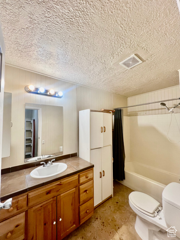 Full bathroom with shower / bath combo, toilet, a textured ceiling, and vanity