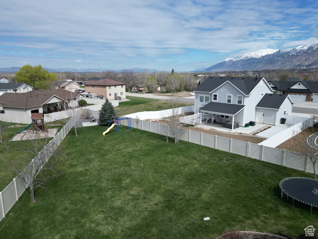 View of yard featuring a trampoline, a playground, and a mountain view