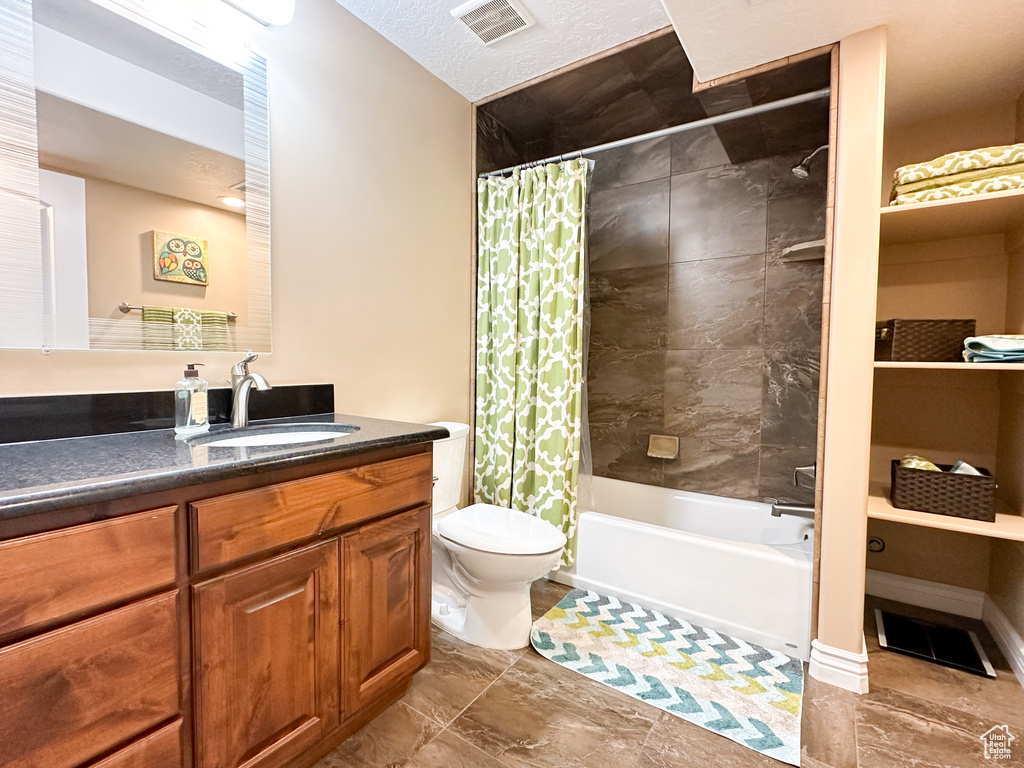 Full bathroom featuring toilet, shower / bath combination with curtain, tile floors, a textured ceiling, and large vanity