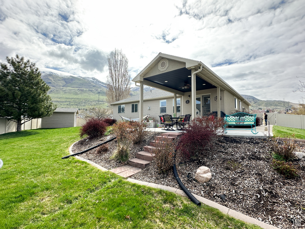 Back of property featuring a patio area, a yard, and a mountain view