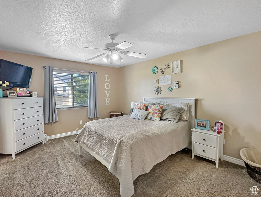 Bedroom featuring carpet floors, ceiling fan, and a textured ceiling