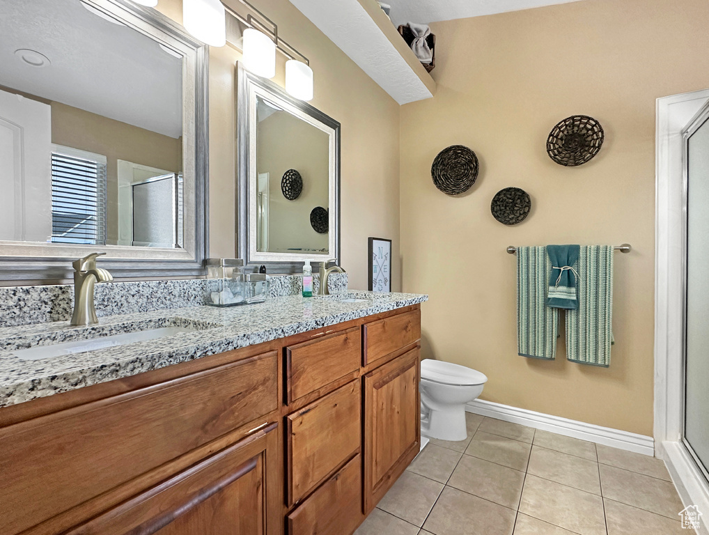 Bathroom featuring walk in shower, tile flooring, toilet, and dual bowl vanity