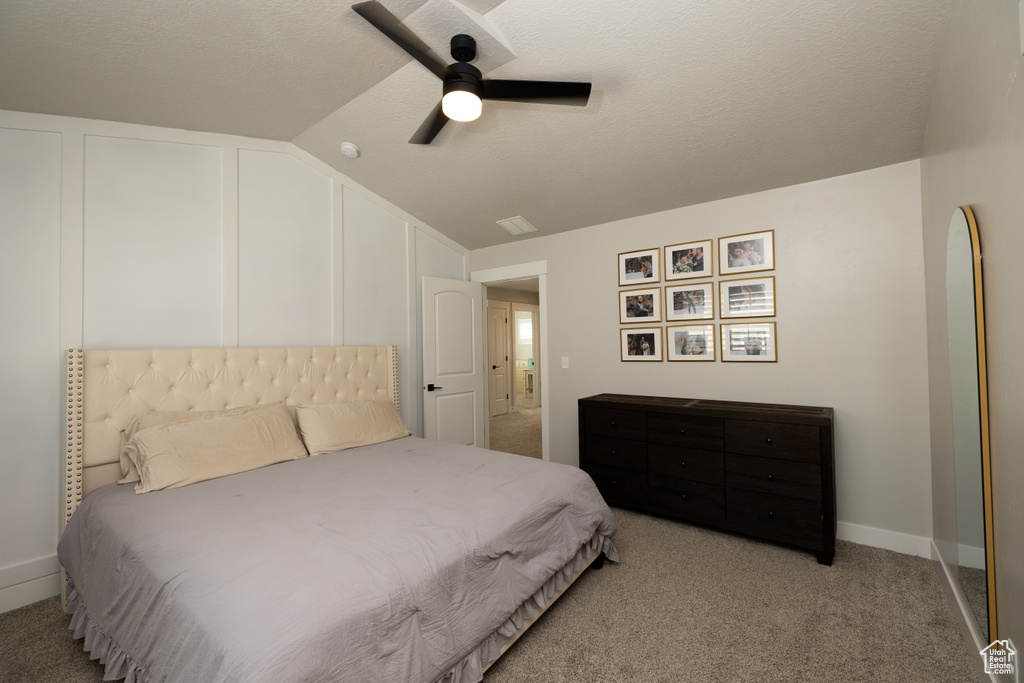 Bedroom featuring a textured ceiling, ceiling fan, vaulted ceiling, and light colored carpet