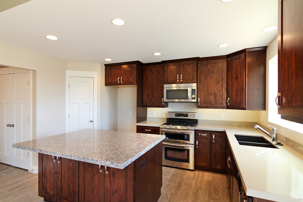 Kitchen featuring light hardwood / wood-style floors, a center island, appliances with stainless steel finishes, and sink